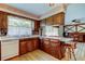 Cozy kitchen with wood cabinets, marble countertops, brick backsplash, and view to living room at 9918 Davis Rd, Tampa, FL 33637