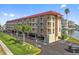 Condo building featuring balconies, covered parking, palm trees, and manicured lawn at 105 Island Way # 126, Clearwater Beach, FL 33767
