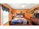 Spacious bedroom with bright orange walls, ceiling fan, and wood-look tile flooring at 15348 Glossy Ibis Rd, Weeki Wachee, FL 34614