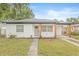 Charming single-story home with fresh white brick, natural wood posts, green door, and a well-manicured lawn at 1713 W Saint John St, Tampa, FL 33607