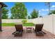 Cozy brick patio in the backyard with two lounge chairs and a small table for outdoor relaxation at 18620 Rococo Rd, Spring Hill, FL 34610