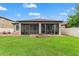 Expansive backyard with well-maintained lawn, patio, and screened-in porch with outdoor seating area at 18620 Rococo Rd, Spring Hill, FL 34610