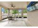 Screened-in patio with seating area, ceiling fan, and views of backyard landscaping through large windows at 18620 Rococo Rd, Spring Hill, FL 34610