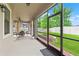 Exterior view of screened-in patio showcasing seating, ceiling fan, and access to lush backyard at 18620 Rococo Rd, Spring Hill, FL 34610