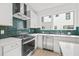 Well-lit kitchen showcasing stainless steel appliances, white cabinetry, quartz countertops, and vibrant green backsplash at 321 15Th N St, St Petersburg, FL 33705