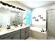 Modern bathroom with dual sinks, soaking tub, walk-in shower, and stylish gray cabinetry at 33560 Castaway Loop, Wesley Chapel, FL 33543