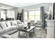 Open-concept living room with modern decor, large windows, and view of the outdoor patio area at 33560 Castaway Loop, Wesley Chapel, FL 33543