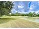 Spacious backyard with green grass and a serene water view under a cloudy sky at 4227 Bethpage Ct, Wesley Chapel, FL 33543