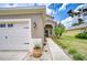 Exterior featuring a two-car garage, walkway, and landscaped garden with palm trees at 4227 Bethpage Ct, Wesley Chapel, FL 33543