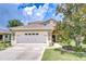 Inviting front exterior with a two-car garage, manicured lawn, and beautiful landscaping at 4227 Bethpage Ct, Wesley Chapel, FL 33543