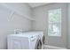 Bright laundry room with white washer and dryer, wire shelving, and window providing natural light at 4227 Bethpage Ct, Wesley Chapel, FL 33543