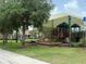 Community playground featuring climbing structures, slides, covered shade, and mature trees at 4227 Bethpage Ct, Wesley Chapel, FL 33543