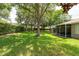 Well-maintained backyard with green grass, established trees, and a screened lanai at 4228 Silver Star Dr, Spring Hill, FL 34609