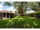Spacious backyard with lush green lawn, mature trees, and a screened-in lanai at 4228 Silver Star Dr, Spring Hill, FL 34609