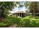 Large backyard with well-maintained lawn, mature trees, and an enclosed lanai at 4228 Silver Star Dr, Spring Hill, FL 34609
