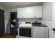Functional laundry area features white cabinets, washer, dryer, and dark blue accent shelving at 4228 Silver Star Dr, Spring Hill, FL 34609