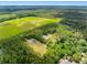Wide aerial view featuring home on wooded lot near a sprawling green landscape under a bright sky at 4261 Burns Rd, Brooksville, FL 34602