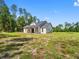 A charming white farmhouse with a dark roof with a covered front porch surrounded by a lush green lawn at 4261 Burns Rd, Brooksville, FL 34602