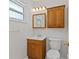Bathroom with white walls, wood cabinets, a white toilet and sink, and a window providing natural light at 4425 Porpoise Dr, Tampa, FL 33617