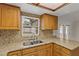 Close-up view of a kitchen featuring granite countertops, wood cabinets, stainless steel sink, and tiled backsplash at 4425 Porpoise Dr, Tampa, FL 33617