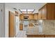 Well-lit kitchen featuring wooden cabinets, granite countertops, tiled backsplash, and modern appliances at 4425 Porpoise Dr, Tampa, FL 33617