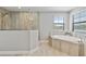 Bathroom featuring soaking tub with stone-look surround and a glass enclosed shower at 4679 Emprise Way, Land O Lakes, FL 34638