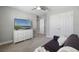 Relaxing bedroom with soft carpet, fan, and large TV over a white dresser for storage at 4679 Emprise Way, Land O Lakes, FL 34638