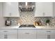 Close-up of kitchen featuring stainless appliances, quartz counters, a mosaic tile backsplash, and white cabinets at 4679 Emprise Way, Land O Lakes, FL 34638