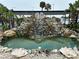 Outdoor water feature with plants and a waterfall effect into a turquoise pool of water at 4851 W Gandy Blvd # B1L8, Tampa, FL 33611