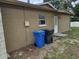 Exterior view of the side of the house with window and exterior door next to trash receptacles at 505 Innergary Pl, Valrico, FL 33594