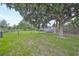 Wide shot of a spacious fenced-in backyard featuring lush green grass and mature shade trees at 7114 Cromwell Park Ln, Apollo Beach, FL 33572