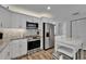 Modern kitchen featuring stainless steel appliances, white cabinets, granite countertops, a mosaic backsplash, and eat-in table at 719 58Th S St, Gulfport, FL 33707
