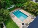 Aerial view of a private backyard pool with stone patio, lounge chairs, and seating area surrounded by lush landscaping at 719 58Th S St, Gulfport, FL 33707