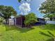 Backyard view of home's screened-in patio, green lawn, and mature fruit trees at 7444 119Th Ave, Largo, FL 33773