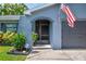 Close up of home's entry with screen door, dark gray garage door, American flag, and lovely landscaping at 7444 119Th Ave, Largo, FL 33773