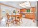 Eat-in kitchen displays wood cabinets, a round table, stainless steel appliances, and access to the living room at 7444 119Th Ave, Largo, FL 33773