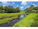 Scenic water view with lush green banks, a canal reflecting the cloudy sky, and a glimpse of nearby homes at 7444 119Th Ave, Largo, FL 33773