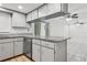 Well-lit kitchen featuring granite countertops, stainless steel dishwasher, and white cabinetry with a view into the living area at 7503 Winchester Dr, Tampa, FL 33615