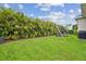 A beautiful backyard featuring lush green grass, a charming swing set, and privacy hedges at 7616 Paradiso Dr, Apollo Beach, FL 33572