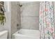 Close up view of a bathtub and shower featuring stylish tiling and floral shower curtain at 7616 Paradiso Dr, Apollo Beach, FL 33572