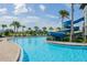 A beautiful community pool offers a thrilling water slide, palm trees, and lounge seating at 7616 Paradiso Dr, Apollo Beach, FL 33572
