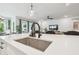 Kitchen with stainless sink, white cabinets and countertops open to dining and living areas at 7616 Paradiso Dr, Apollo Beach, FL 33572