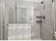 Walk-in shower featuring neutral tile, glass door, rainfall showerhead, and built-in shelving at 7616 Paradiso Dr, Apollo Beach, FL 33572
