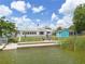 Back of house featuring a waterfront lawn, a shed, and seating with umbrella at 8014 Lotus Dr, Port Richey, FL 34668