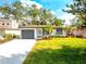 Charming single-story home with lush green lawn, a gray garage door, and well-manicured landscaping at 8335 42Nd N Ave, St Petersburg, FL 33709