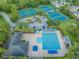 Aerial view of community amenities: pool, tennis courts, and parking, all surrounded by mature trees at 9806 Bennington Dr, Tampa, FL 33626