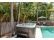Inviting hot tub next to a pool with lush landscaping and patio seating under an umbrella at 1 Mandarin Ter, Safety Harbor, FL 34695