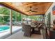 Outdoor kitchen and dining area on covered patio with wood ceiling and view of the pool at 1 Mandarin Ter, Safety Harbor, FL 34695