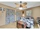 Calming bedroom features hardwood floors, patterned curtains, ceiling fan, and a unique trunk at 11187 Blythville Rd, Spring Hill, FL 34608