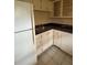 This kitchen contains a refrigerator, stainless steel sink, white cabinets and tile flooring at 11485 Oakhurst Rd # 1200-214, Largo, FL 33774